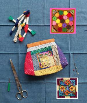 Buntes, besticktes Täschchen, umgeben von Stickgarn, Schere und Stickmustern