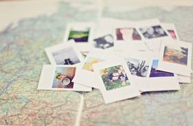 Mehrere Polaroid-Fotos liegen verstreut auf einer Landkarte